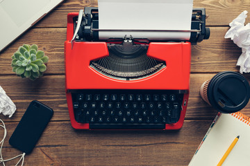 Top view of vintage red typewriter machine on the old wooden working desk