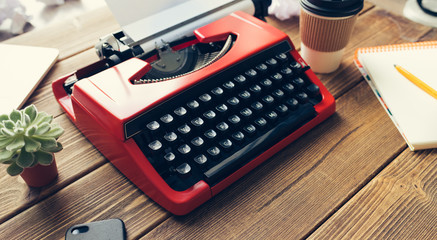 Top view of vintage red typewriter machine on the old wooden working desk