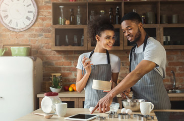 Happy african-american couple baking and using tablet
