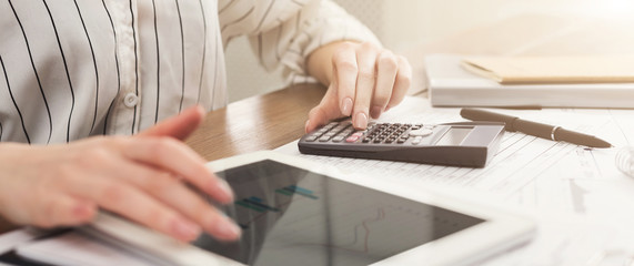 Woman counting finances on tablet and calculator