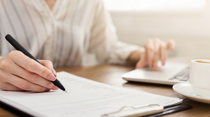 Young female entrepreneur on laptop and writing notes