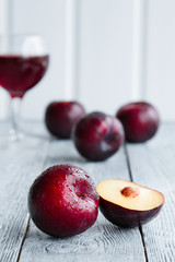 plums on wooden background with a glass of wine