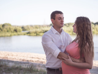 Obraz premium Happy young pregnant couple resting in the Park. Loving husband and wife