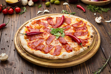 Pizza pepperoni with mozzarella cheese, salami and arugula on wooden background
