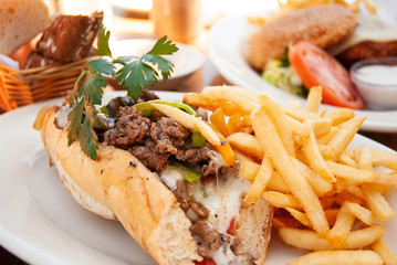 American beef cheese steak sub  sandwich and fries on white plate