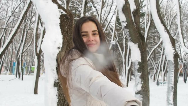 A girl plays with snowballs. The girl throws snow at the camera.