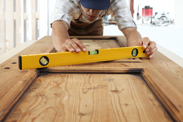 carpenter at work with spirit level on wood background