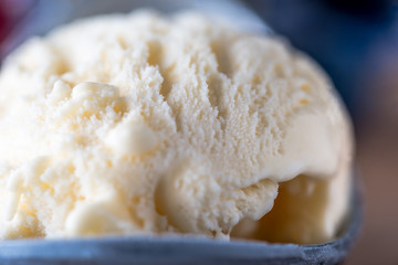 A single scoop of vanilla ice cream on a wooden board