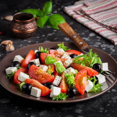 Salad with tomatoes, feta, olives and Basil, serving on a dark background