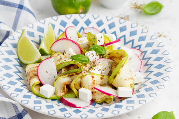 Fresh healthy salad with grilled zucchini, radish, feta, lime, tasty snack