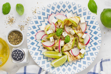 Fresh healthy salad with grilled zucchini, radish, feta, lime, tasty snack