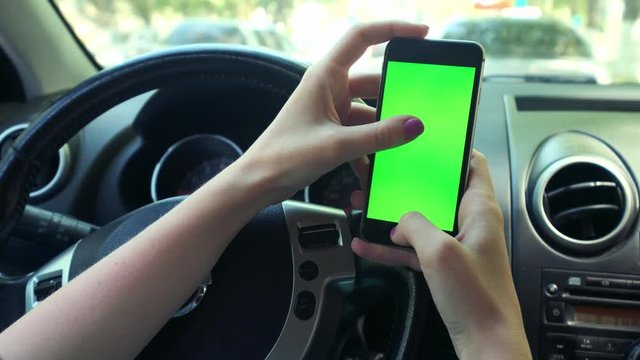 Girl Driver closeup, greenscreen in the car, urban city background greenscreen chrome key 4k. Sweeps his hand across the screen to the left