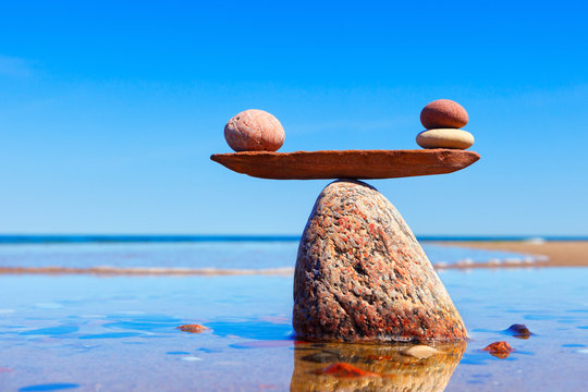 Symbolic scales made of stones on the sea background. Concept of harmony and balance.