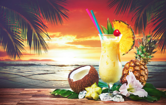 Pina colada fresh cocktail drink served on the beach at sunset