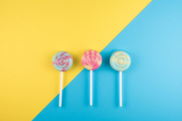 assortment of colorful lollipop over blue and yellow colored background. sweet food concept