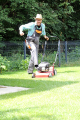 G&auml;rtner mit Latzhose und rotem Rasenm&auml;her