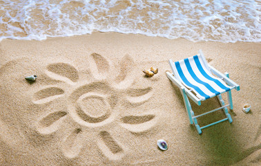 Deckchair on a beach with a sun drawn on the sand