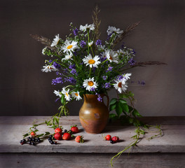 Still life with bouquet of chamomiles and lavender on wooden table. Strawberry and currant