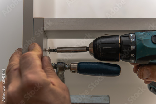 A Carpenter Screws Kitchen Cabinets He Fixed The Cabinets With A