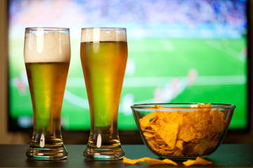 beer glasses and chips in front of tv - watching world cup football at home - soccer supporters