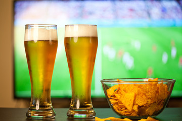 beer glasses and chips in front of tv - watching world cup football at home - soccer supporters