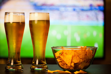 beer glasses and chips in front of tv - watching world cup football at home - soccer supporters
