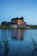 Fototapeta na wymiar Beautiful view of lit 13th century Häme Castle and its reflections on lake Vanajavesi in Hämeenlinna, Finland, in the evening.