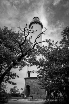black and white photo of a lighthouse behind some branches
