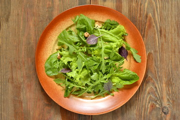 Fresh green salad with spinach, arugula, lettuce, herbs and nuts, top view
