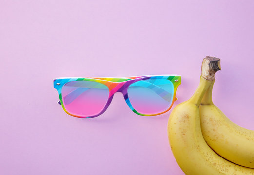 Yellow bananas and sunglasses on clear pink background. Above view