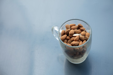 Glass cup and almonds on metal grey background. Above view