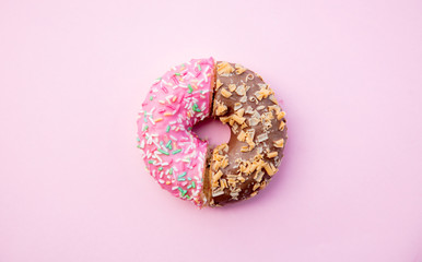 Two parts of donuts, pink and chocolate on pink background