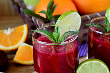 Smoothie with beet and orange in a glass decorated with mint and a slice of lime