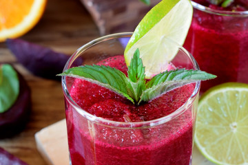 Smoothie with beet and orange in a glass decorated with mint and a slice of lime