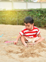 Asian boy playing with sand in playground
