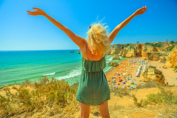 Tourism in Portugal, Europe. Lifestyle blonde female tourist on sandstone rocks of Praia Dona Ana,...