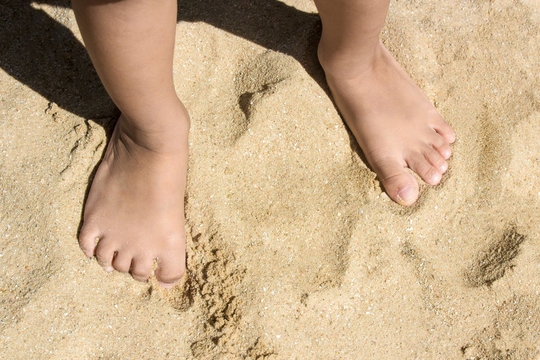 Legs of children stand on the beach with copy space