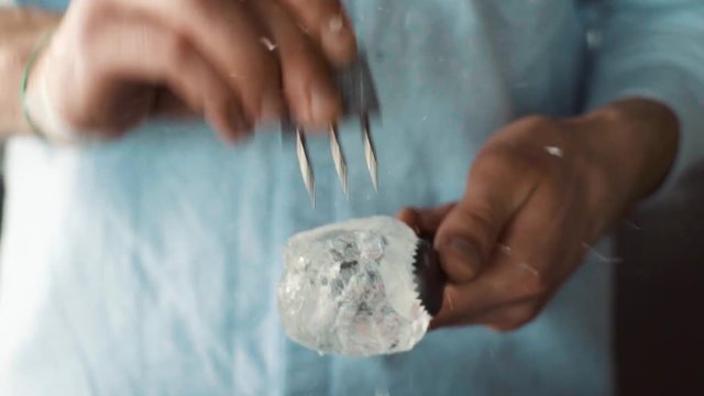 Bartender carves ice using ice pick
