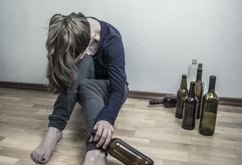 A drunk woman with a bottle of wine. Depressive girl. Alcoholics.