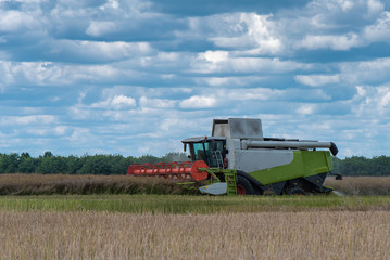 a large white harvester in the field of wheat and corn