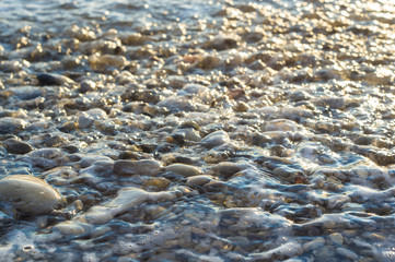 pebble stones on the sea beach, the rolling waves of the sea with foam