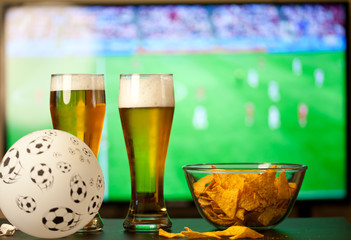 beer glasses and chips in front of tv - watching world cup football at home - soccer supporters