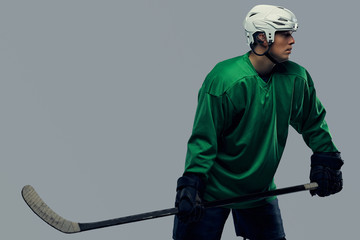 Professional hockey player trains in full equipment with gaming stick against a gray background.