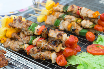 Barbecue sticks on grille at street market.