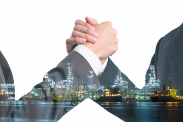 Double exposure of Business people gripping hands on Power plant with shipping boat at night time.  Investment in Energy concept.