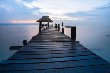 A wooden walk way through the hut under sunrise at early morning on ocean view 