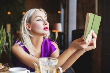 Blonde Woman Reading Book and Sitting in Restaurant