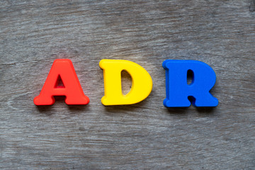 Colorful plastic alphabet in word ADR (Abbreviation of adverse drug reaction) on wood background