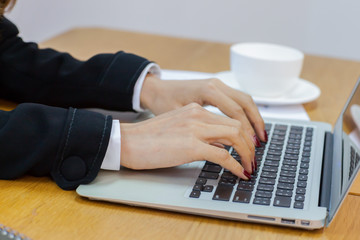 Business people are hand typing on silver color laptop computer put on table