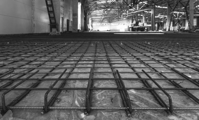 reinforcement frame of the floor prepared for pouring concrete in an industrial room, black and white photo
